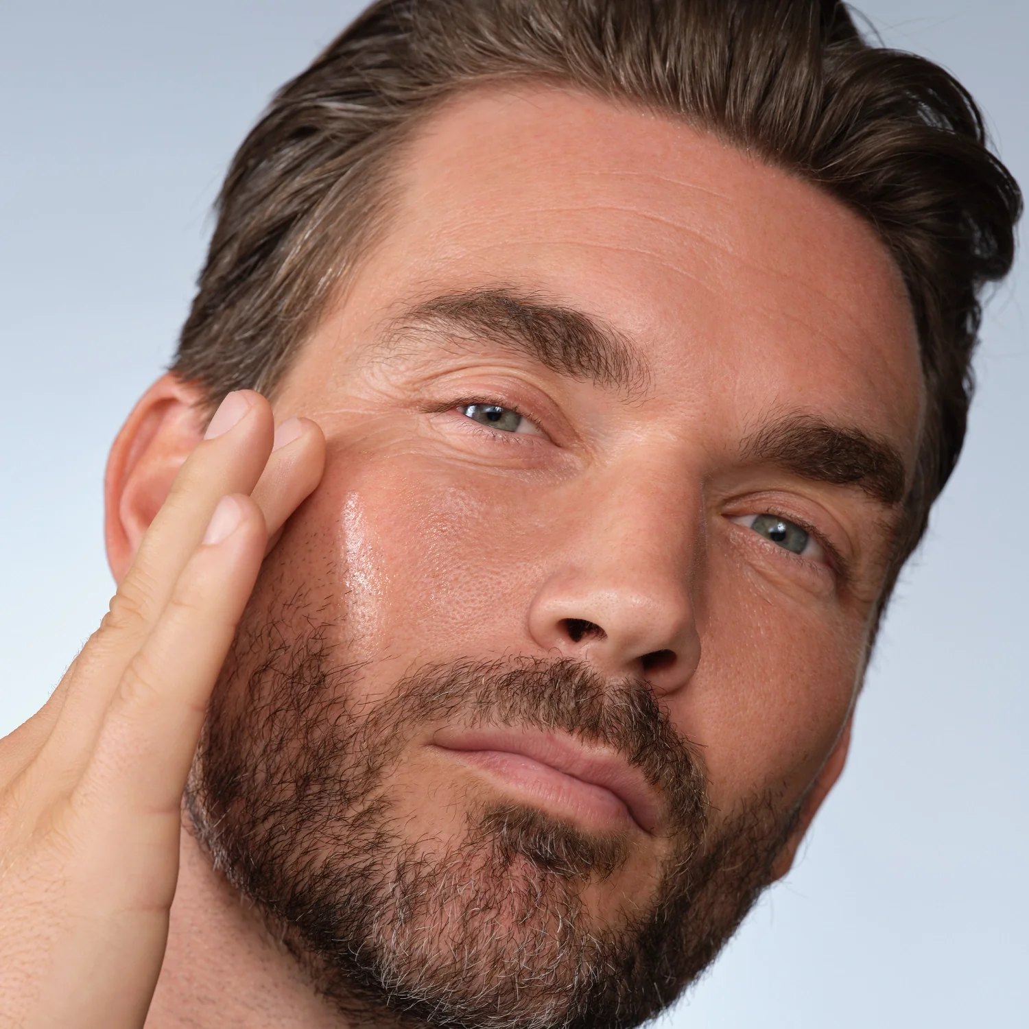 A man applying Caldera plus Lab serum to his cheek.