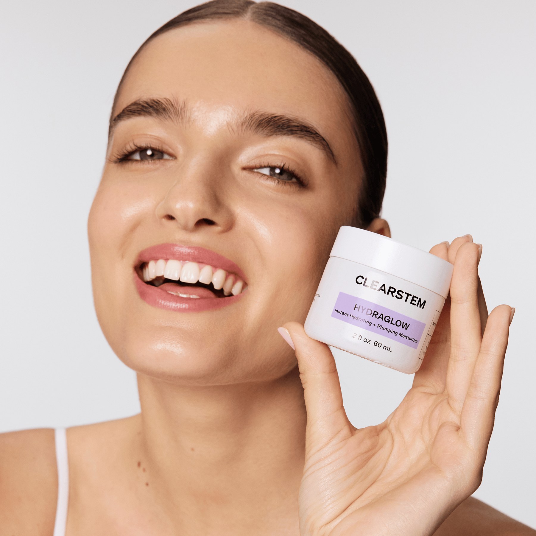 A model holds a jar of HYDRAGLOW Plant Stem Cell Moisturizer, the brand's best-selling skincare product.