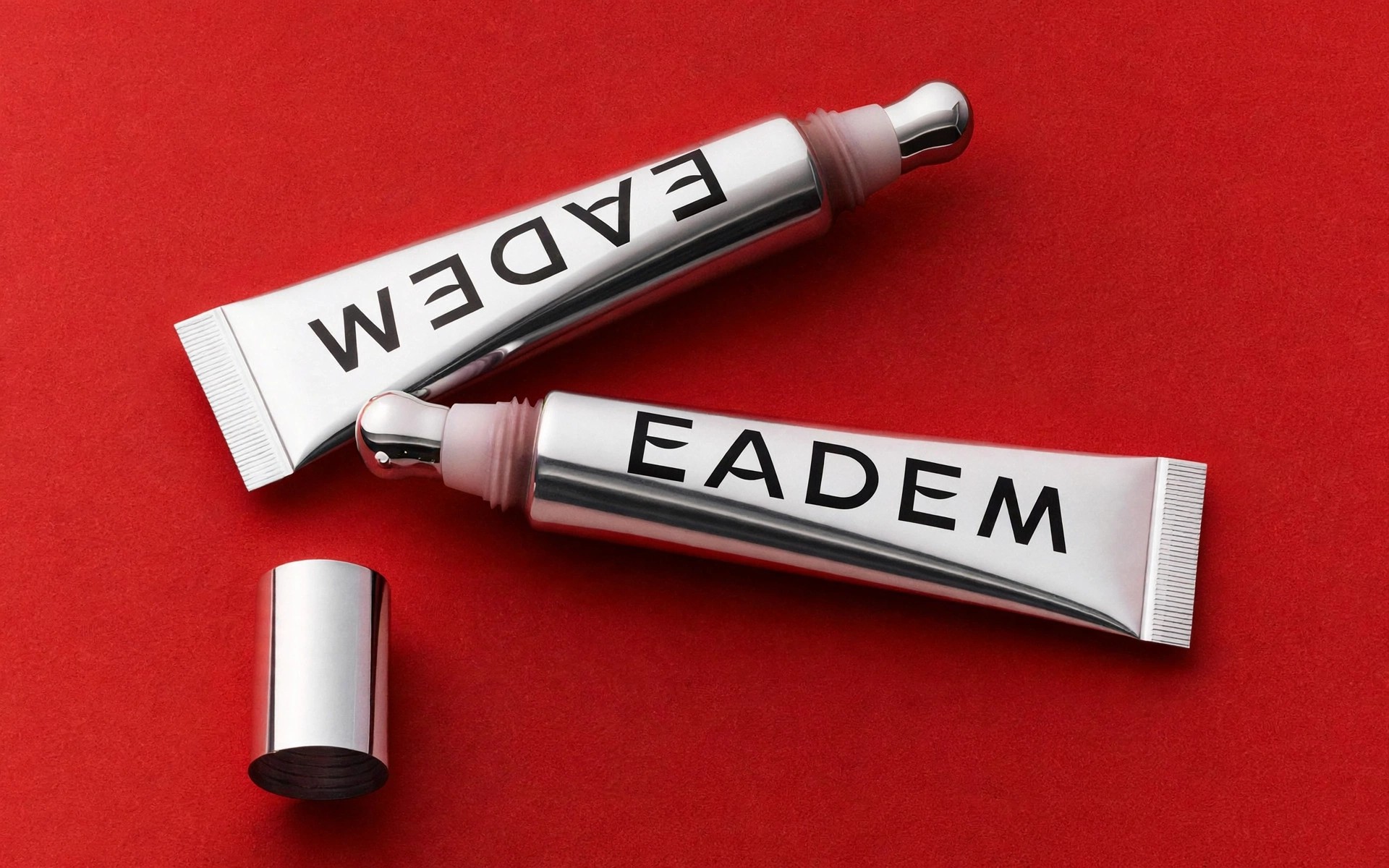 Two silver Eadem tubes arranged on red background.