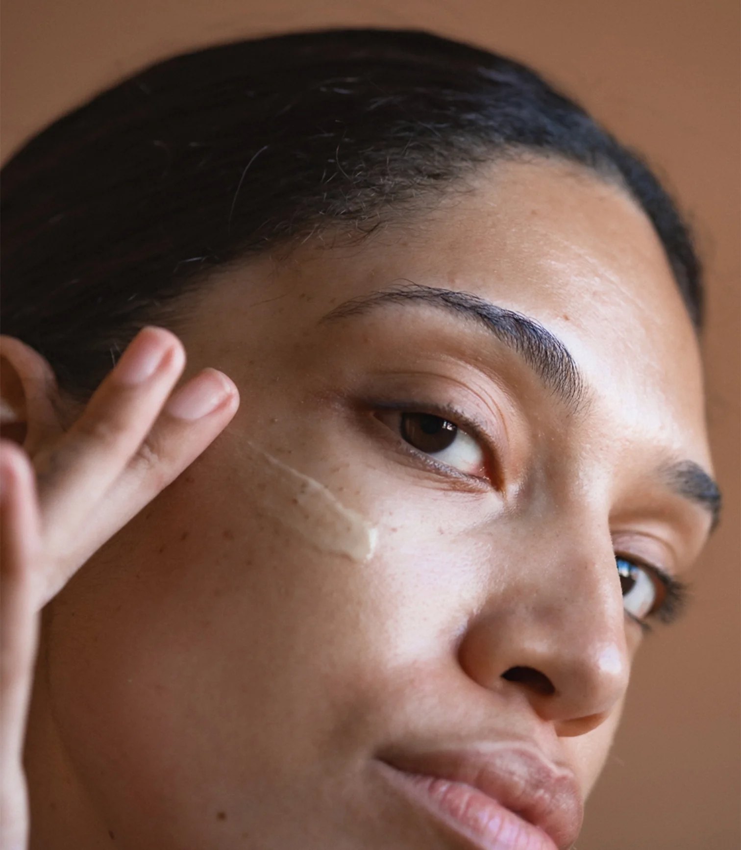 Woman applying light cream texture beside her eye area.