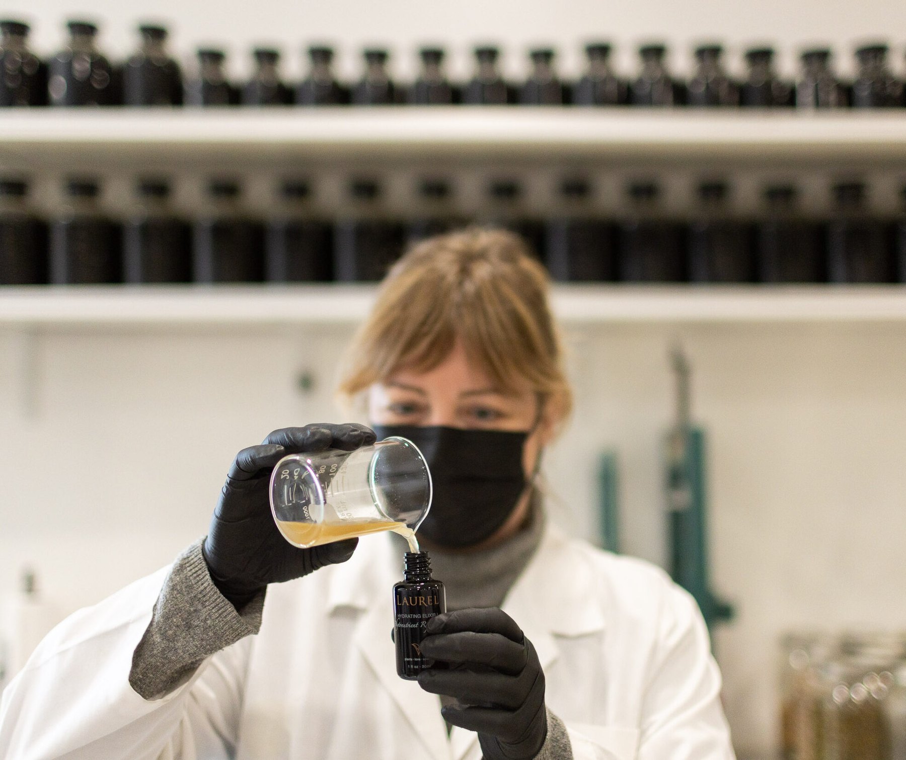 A lab worker pours liquid into a Laurel bottle.