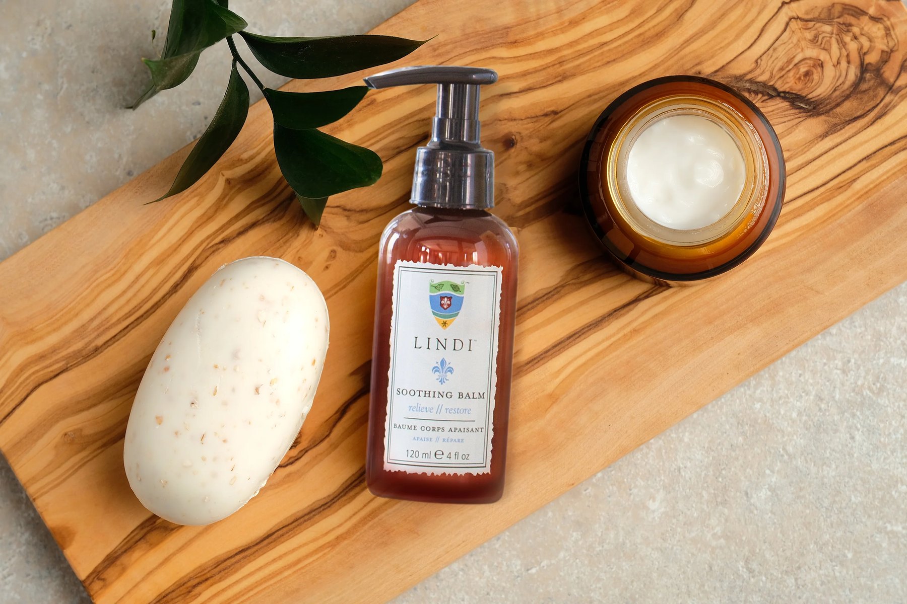 Lindi Soothing Balm bottle with open jar on wooden tray.