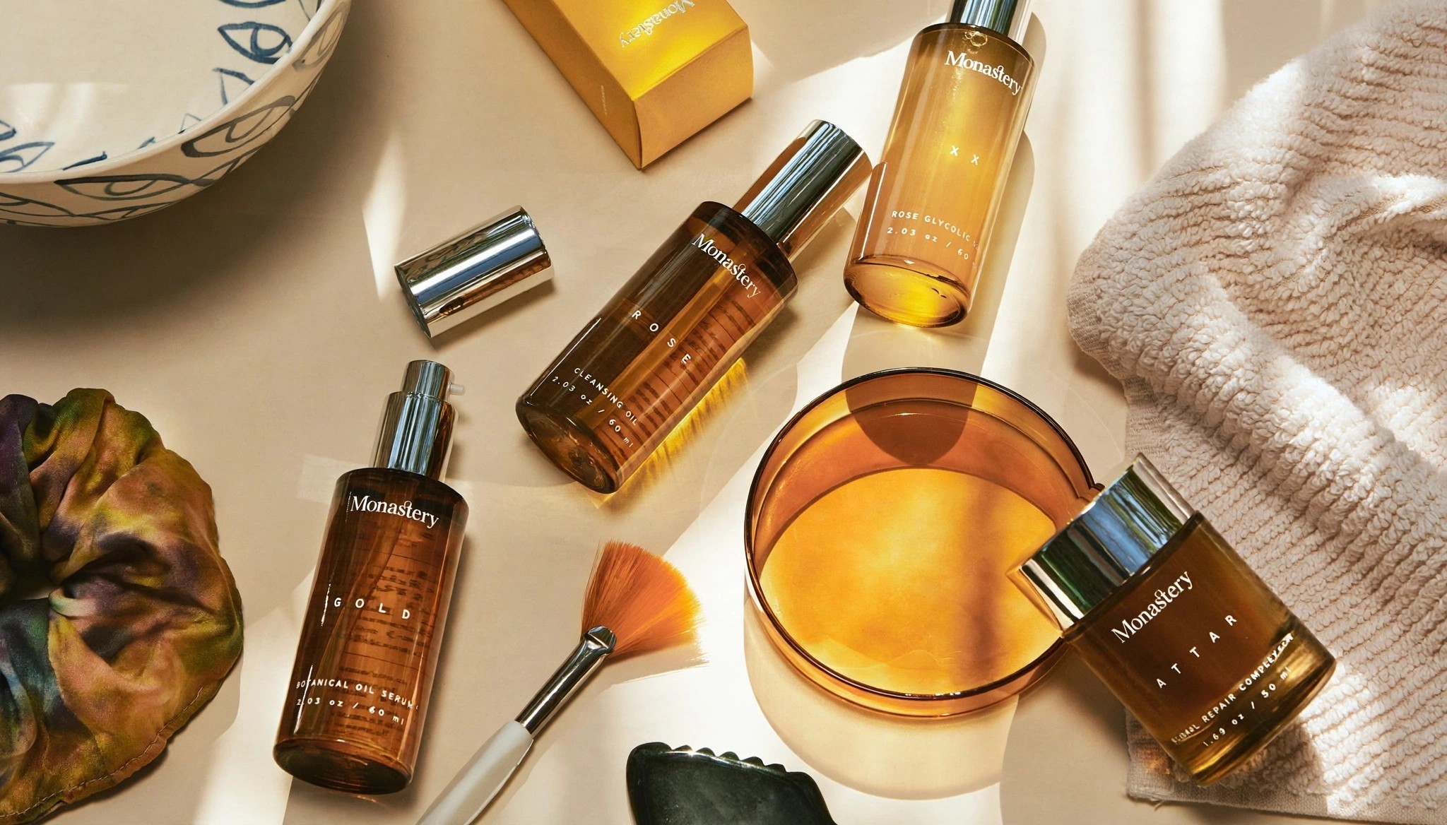 Monastery amber oil bottles styled with brush towel and sunlight.