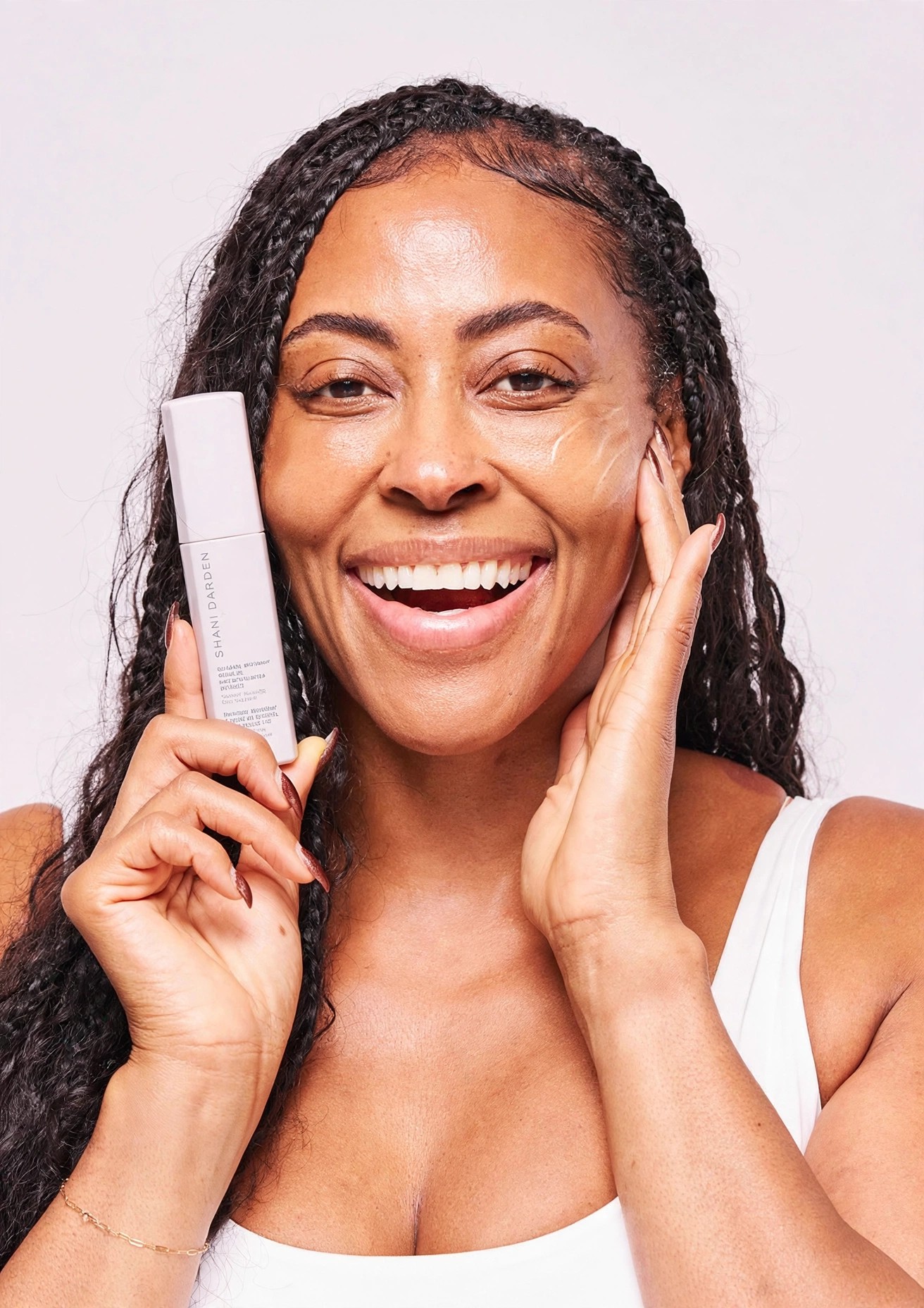 Woman smiling while holding Retinol Reform near cheek.