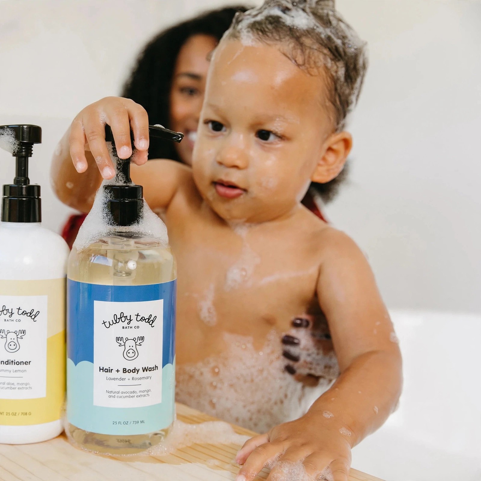 Toddler with soap suds beside Tubby Todd Hair Body Wash.