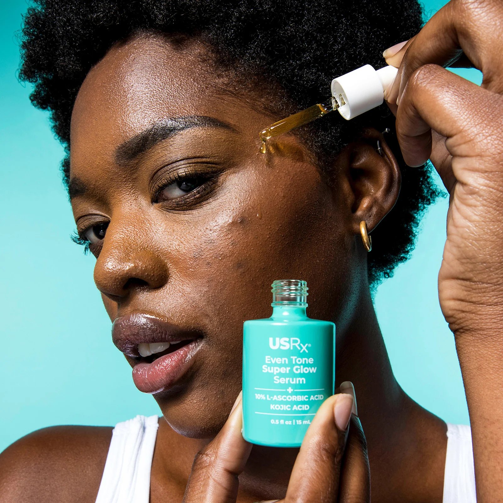 Woman applying Even Tone Super Glow Serum to her cheek.